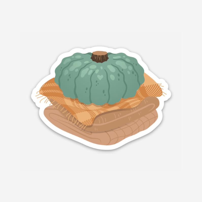 blue pumpkin on a stack of patterned fall blankets.