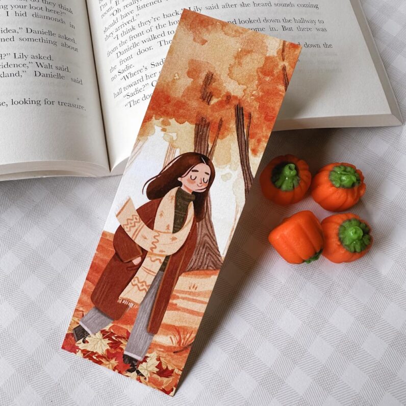 Bookmark with a girl dressed in fall atire walks through leaves.