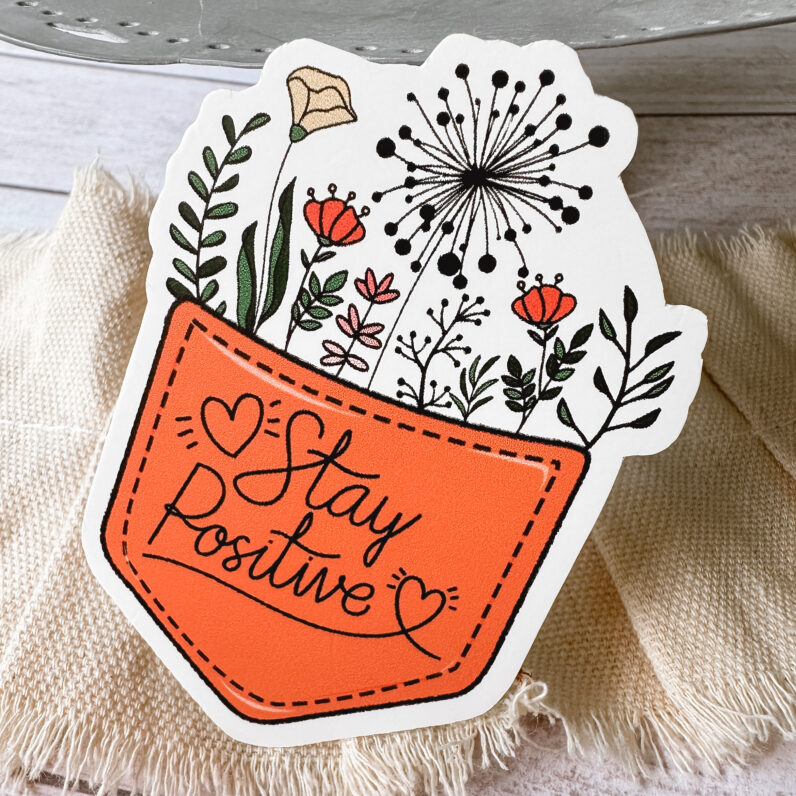 vinyl sticker looks like a stitched pocket with the words "stay positive" and a bouquet of flowers coming out of the pocket.